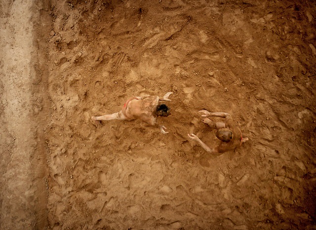 Two wrestlers practising the ancient Indian sport of Kushti in a pit they had hacked into the ground two hours earlier. 